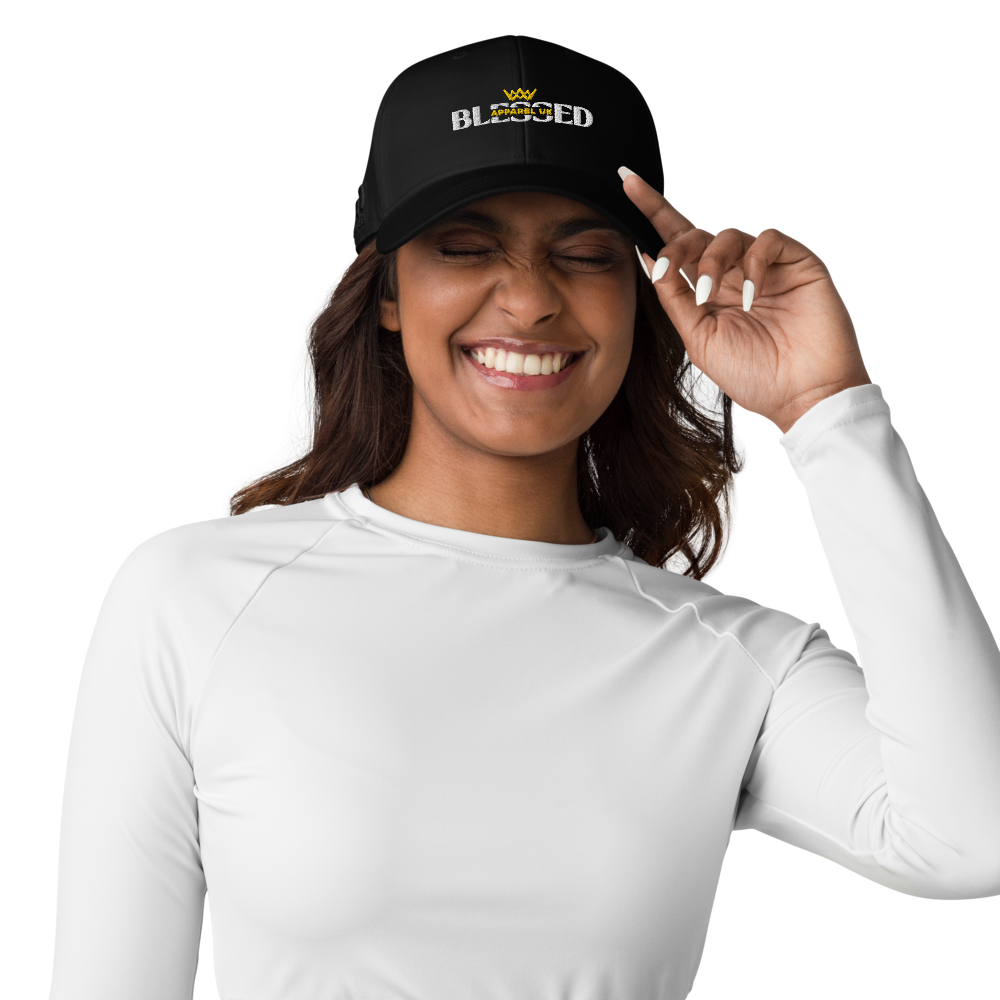Image of a smiling person holding the peak of a baseball cap with blessed apparel logo in yellow and white.