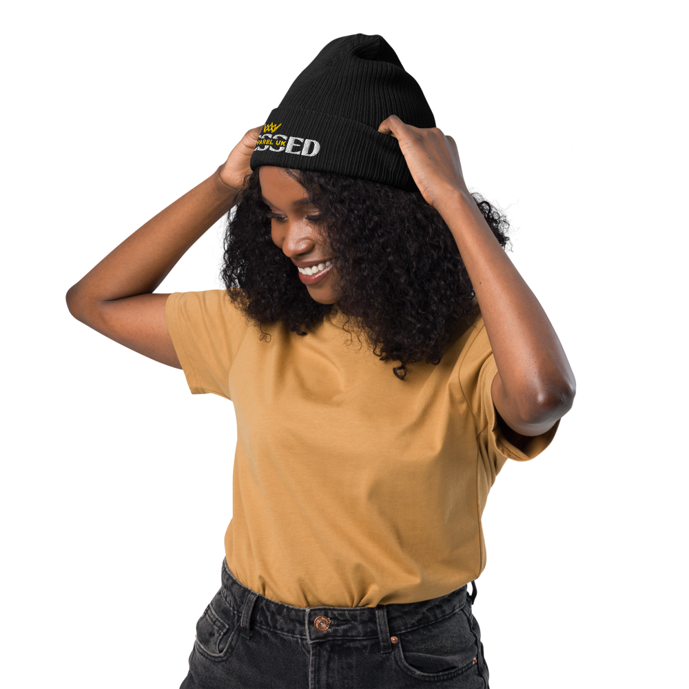 Image of a smiling person wearing a beenie hat with blessed apparel logo in yellow and white.