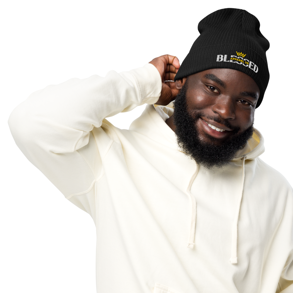 Image of a smiling person wearing a beenie hat with blessed apparel logo in yellow and white.