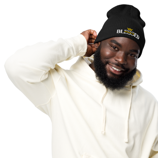 Image of a smiling person wearing a beenie hat with blessed apparel logo in yellow and white.