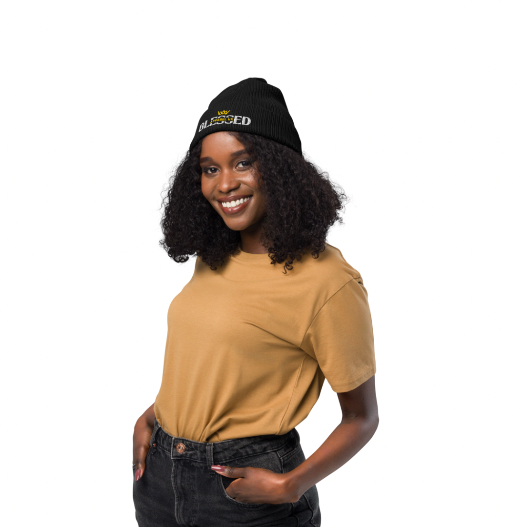 Image of a smiling person wearing a beenie hat with blessed apparel logo in yellow and white.