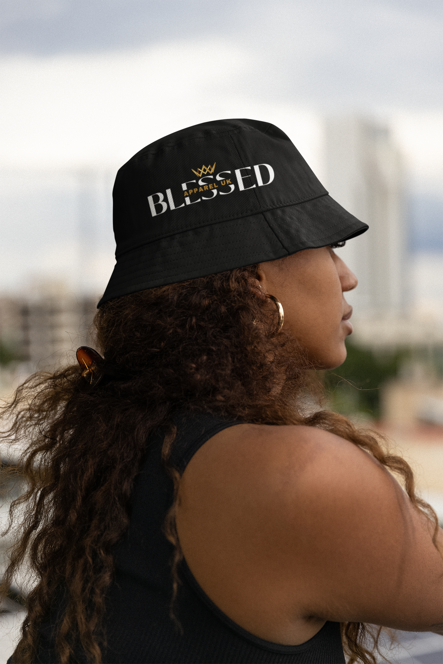 Image of a person wearing a bucket hat with blessed apparel logo in yellow and white.