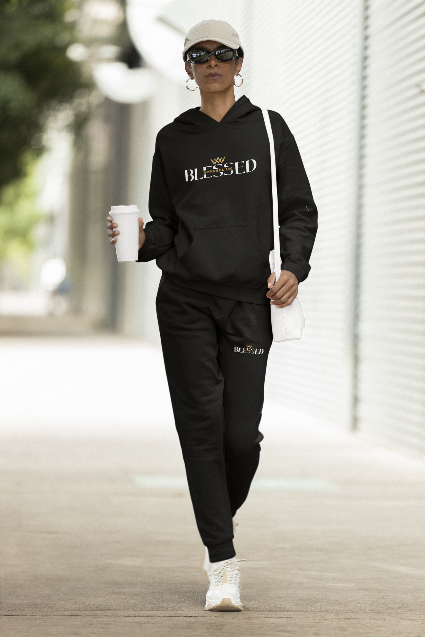 mage of a person walking down the street wearing black hoodie and sweatpants with blessed apparel logo in yellow and white.