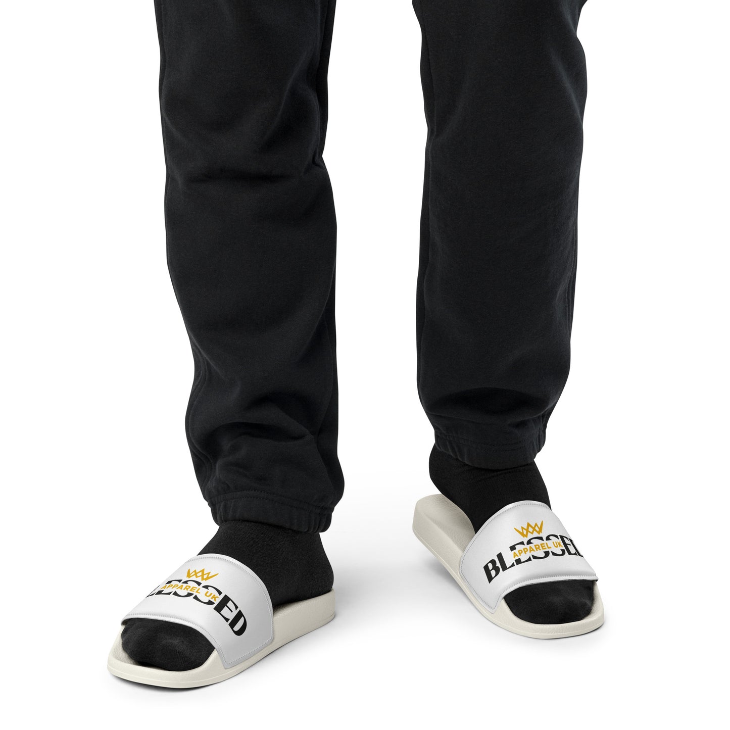 Close up image of a person 's legs and feet wearing a white pair of slides with blessed apparel logo in yellow and white.