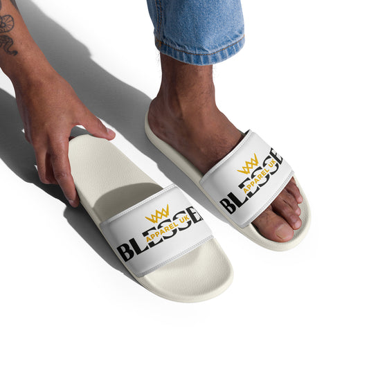 Close up image of a person 's legs and feet wearing a white pair of slides with blessed apparel logo in yellow and white.