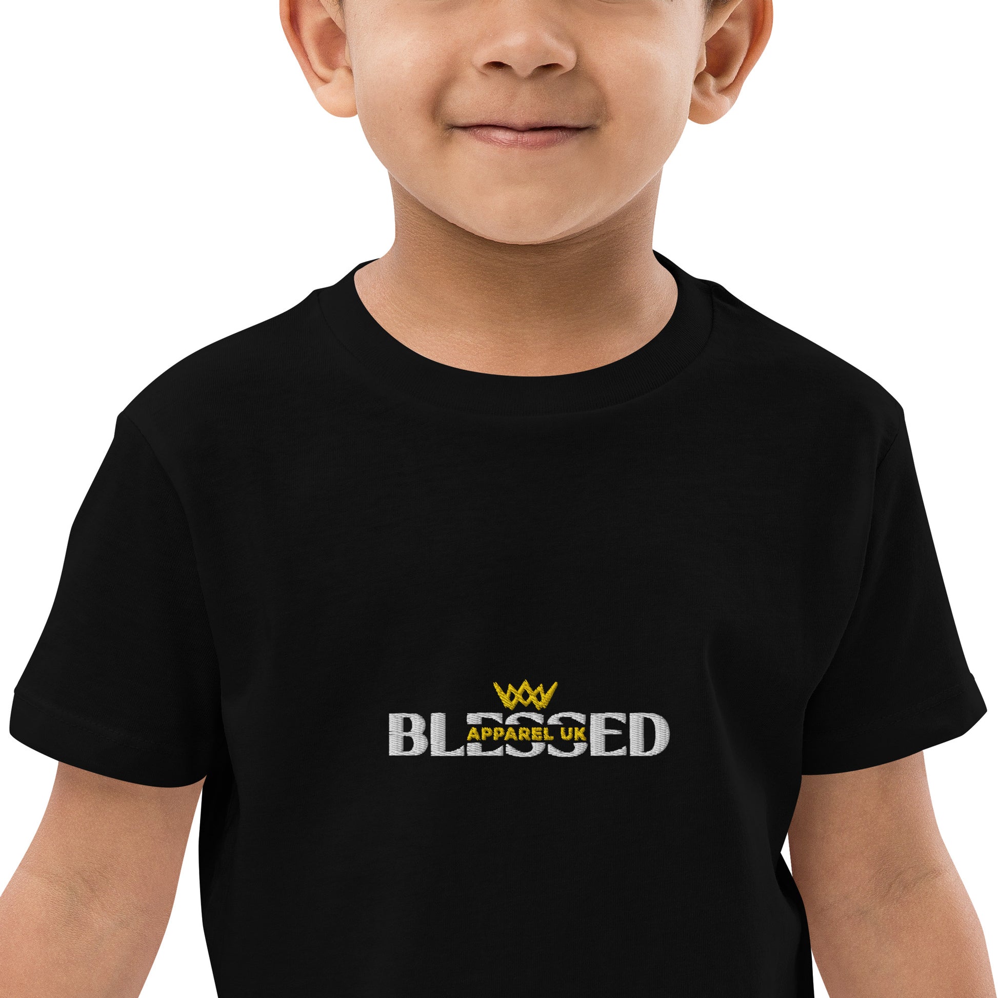 A close-up image of a child wearing a black t-shirt with the Blessed Apparel UK logo in gold and white across the chest.