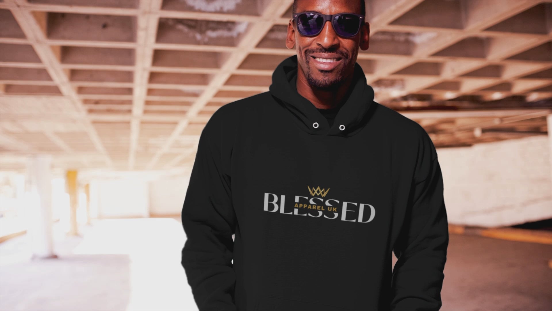 Video of a person walking, wearing a black hoodie with blessed apparel logo in yellow and white.