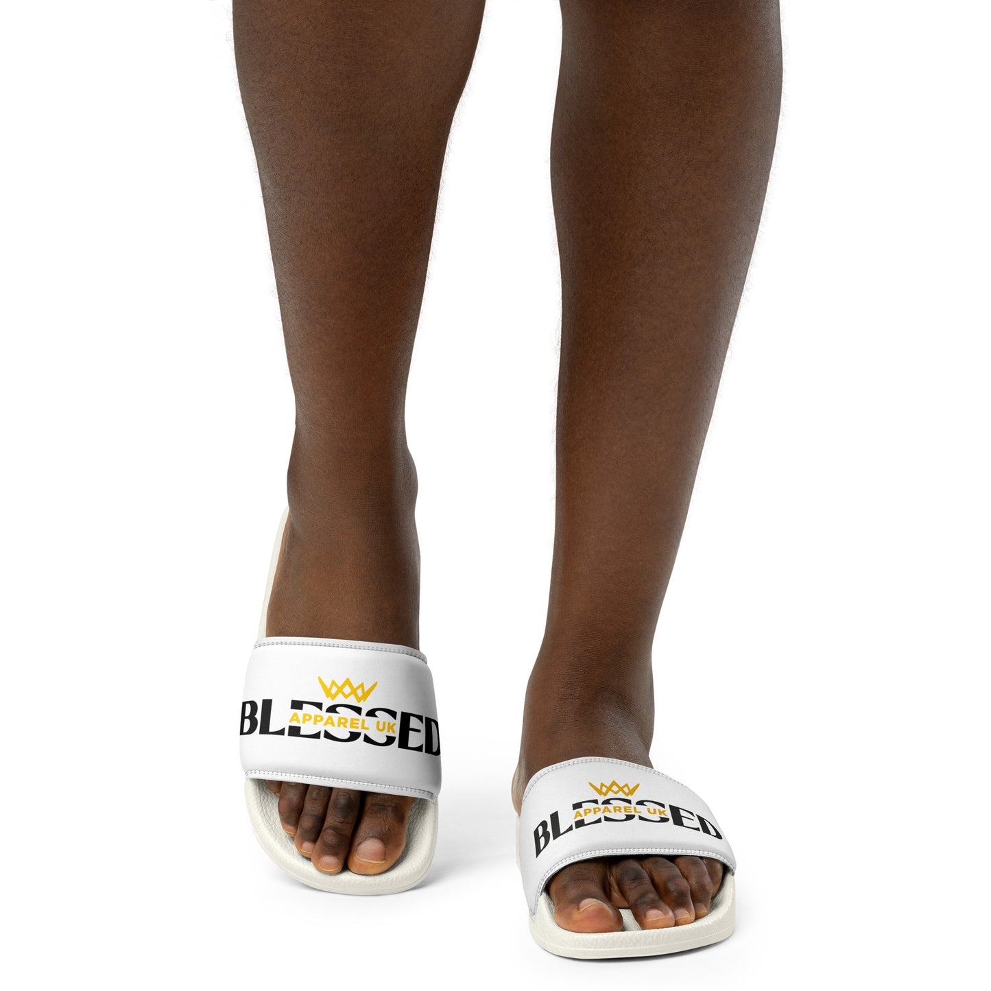 Close up image of a person 's legs and feet wearing a white pair of slides with blessed apparel logo in yellow and white.